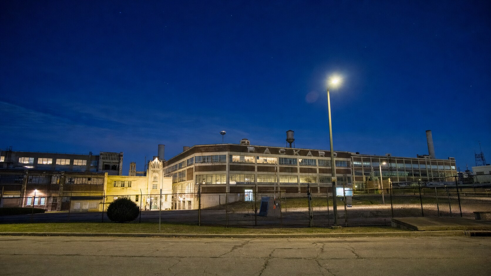 Wide blue-hour view of Packard Automotive Plant with cobalt sky and warm artificial lighting on the landmark