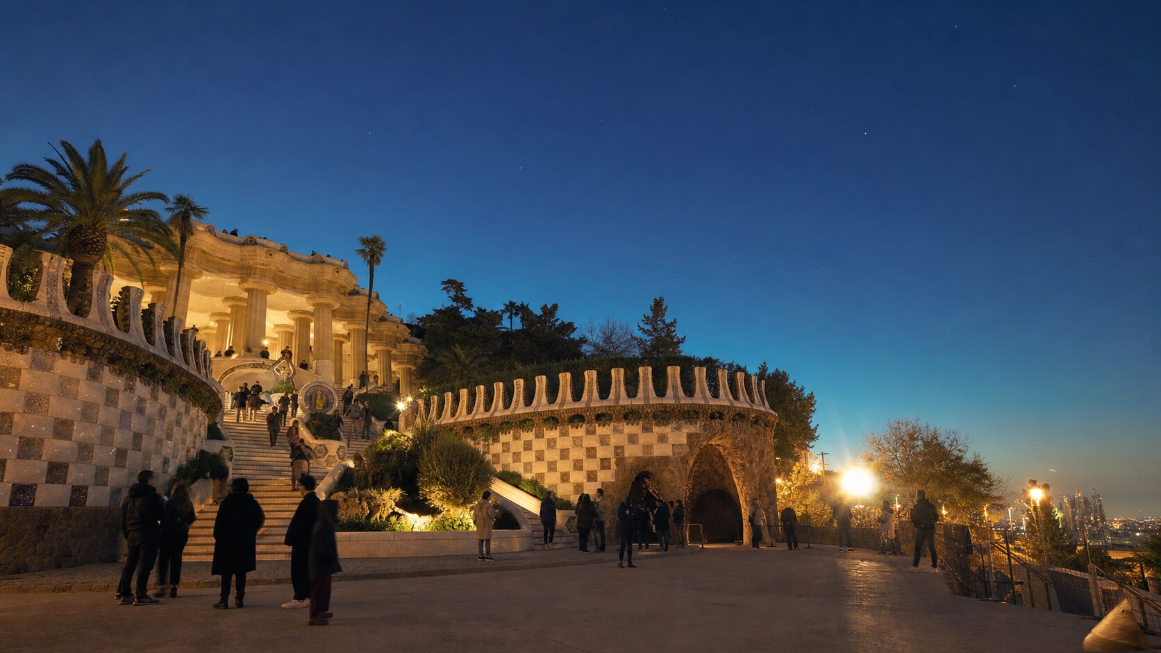 Wide blue-hour view of Park Guell with cobalt sky and warm artificial lighting on the landmark