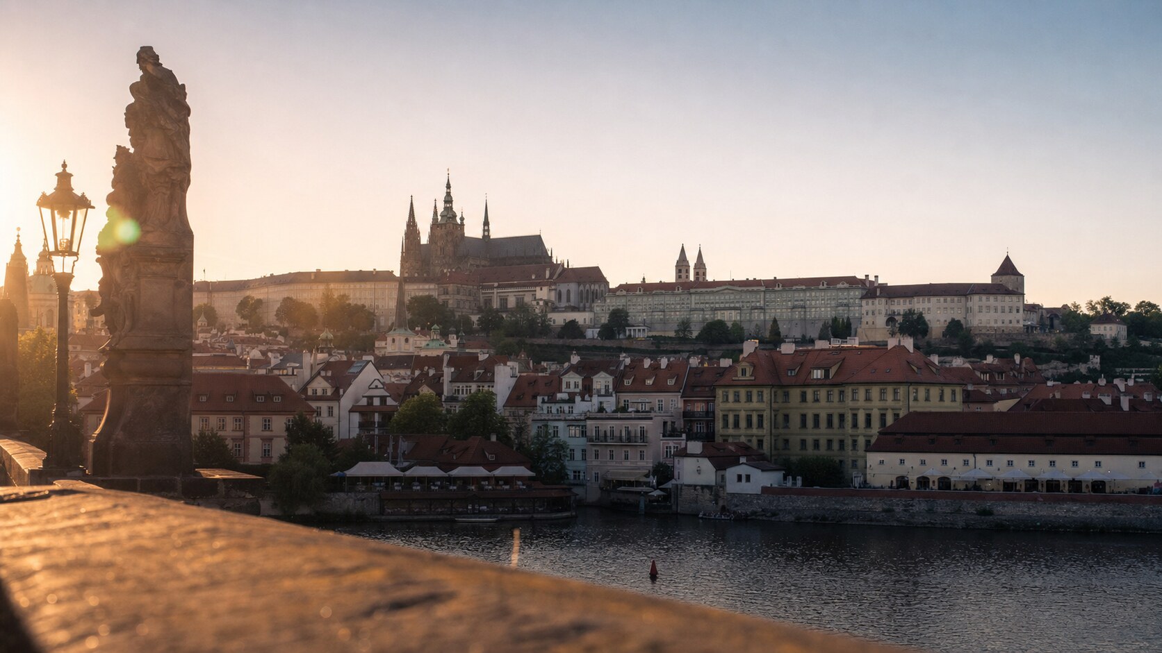Prague Castle photographed at golden hour from the most popular hero-shot vantage point, with dramatic side-lighting on the structure