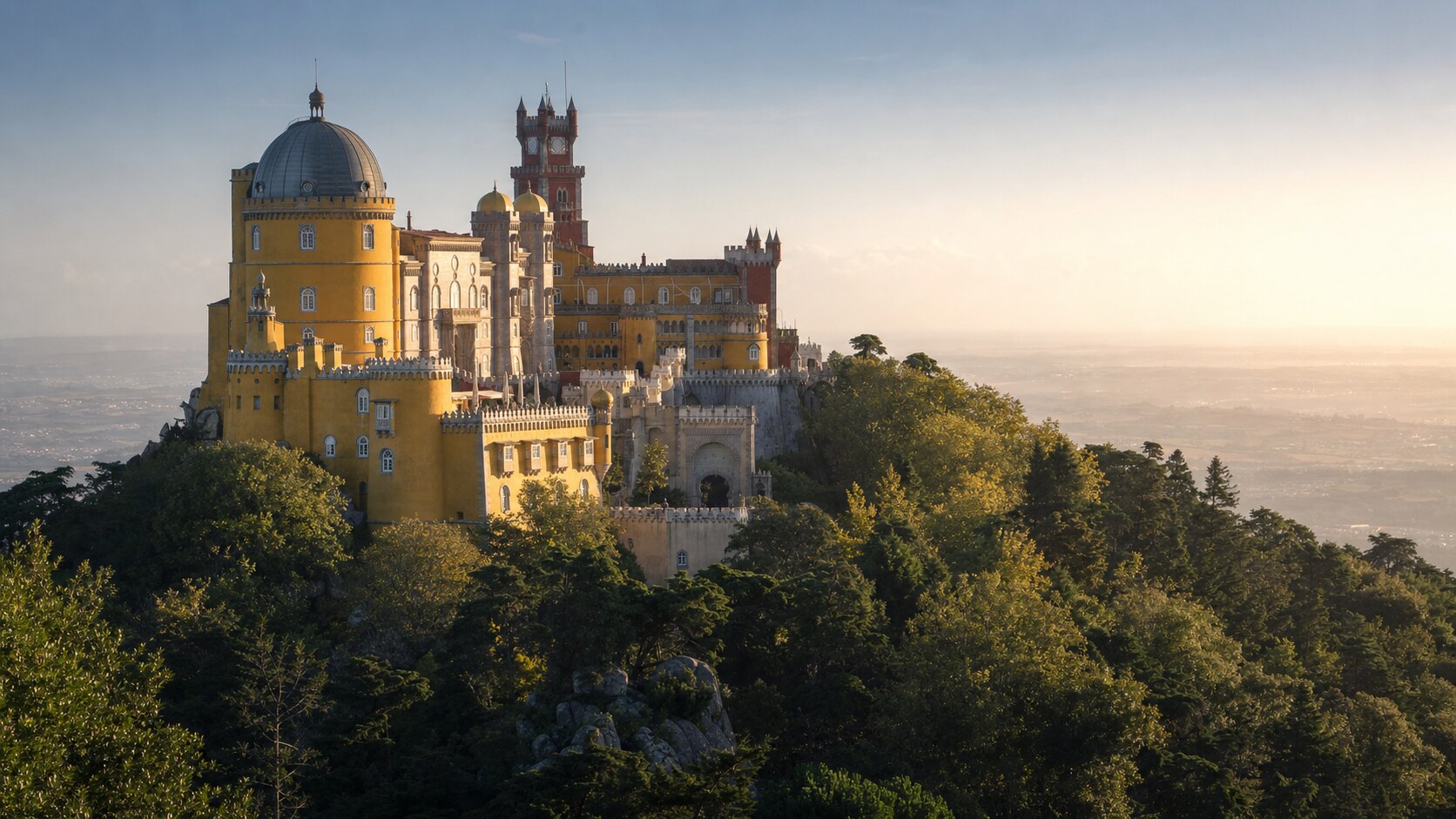 Sintra Pena Palace photographed at golden hour from the most popular hero-shot vantage point, with dramatic side-lighting on the structure