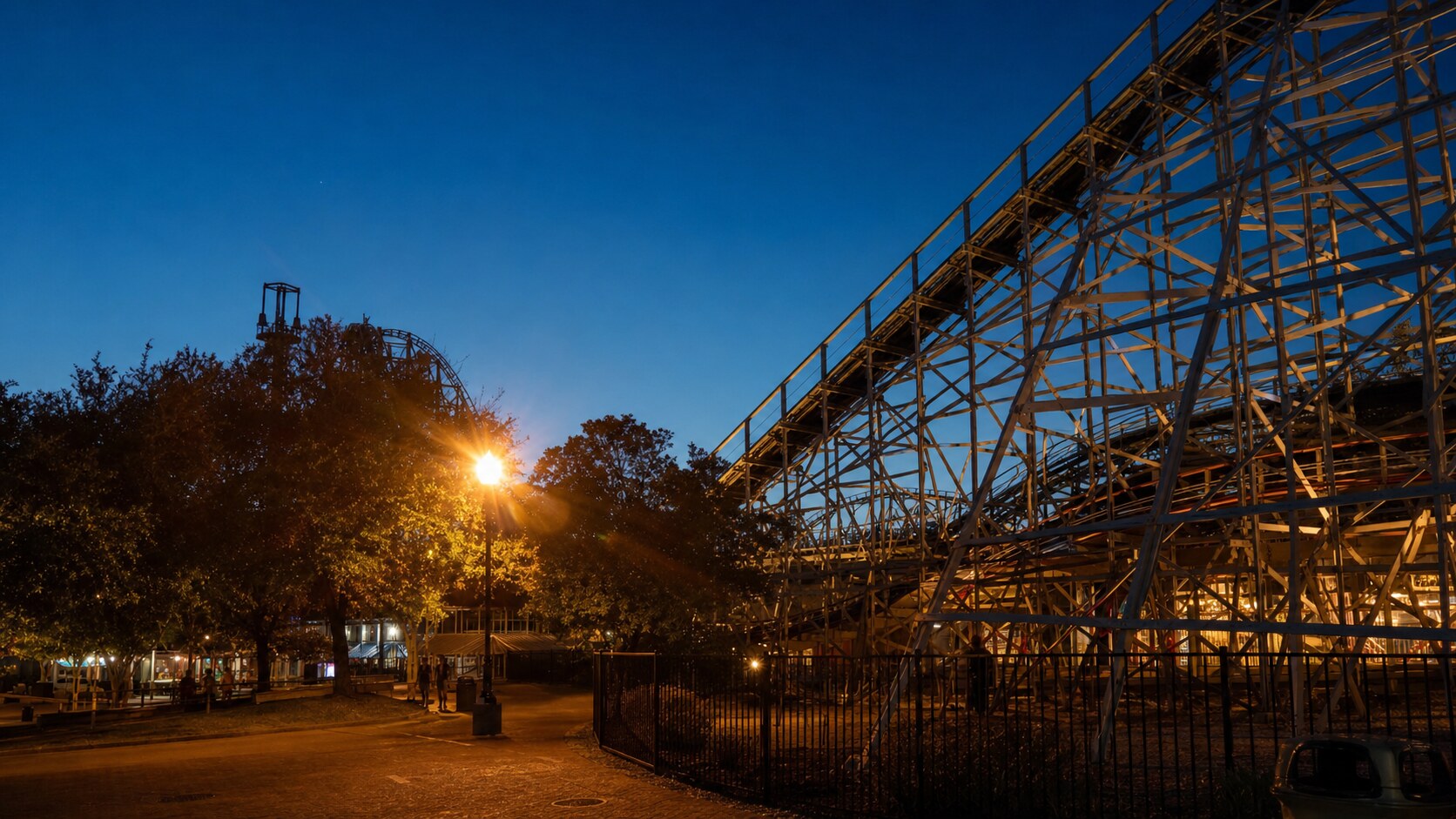 Wide blue-hour view of Six Flags New Orleans with cobalt sky and warm artificial lighting on the landmark