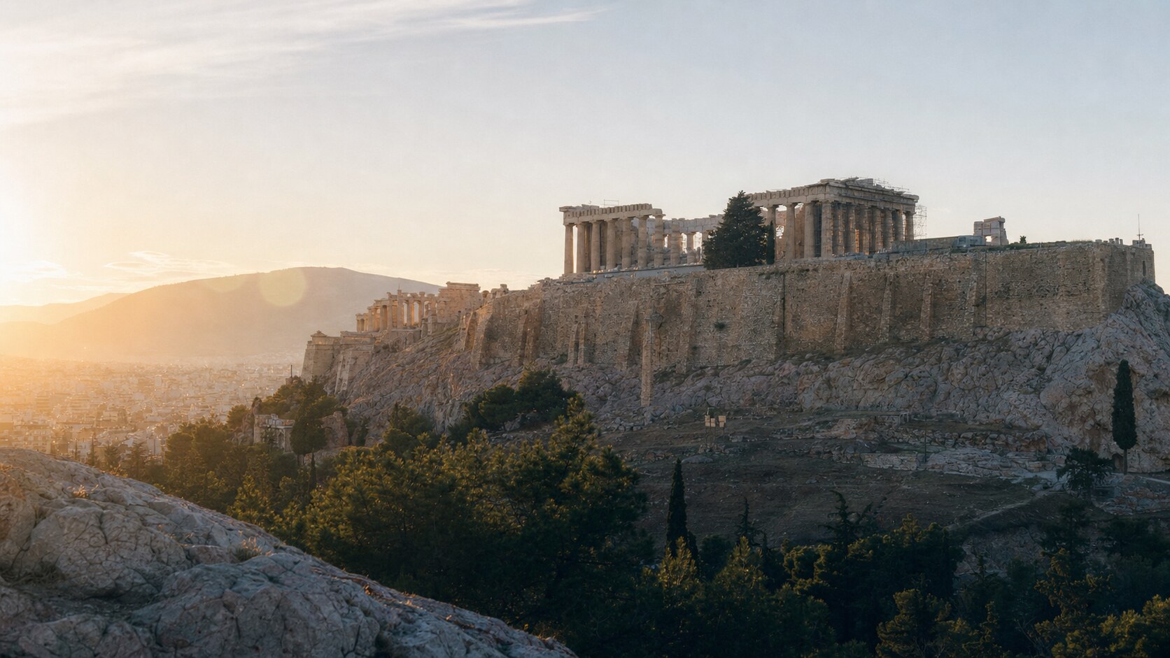 The Acropolis photographed at golden hour from the most popular hero-shot vantage point, with dramatic side-lighting on the structure