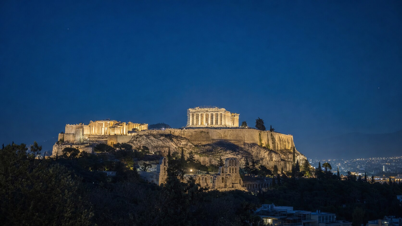 Wide blue-hour view of The Acropolis with cobalt sky and warm artificial lighting on the landmark