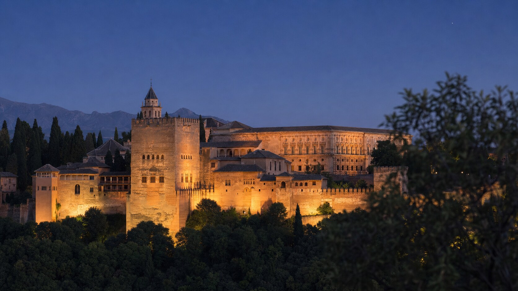 Wide blue-hour view of The Alhambra with cobalt sky and warm artificial lighting on the landmark