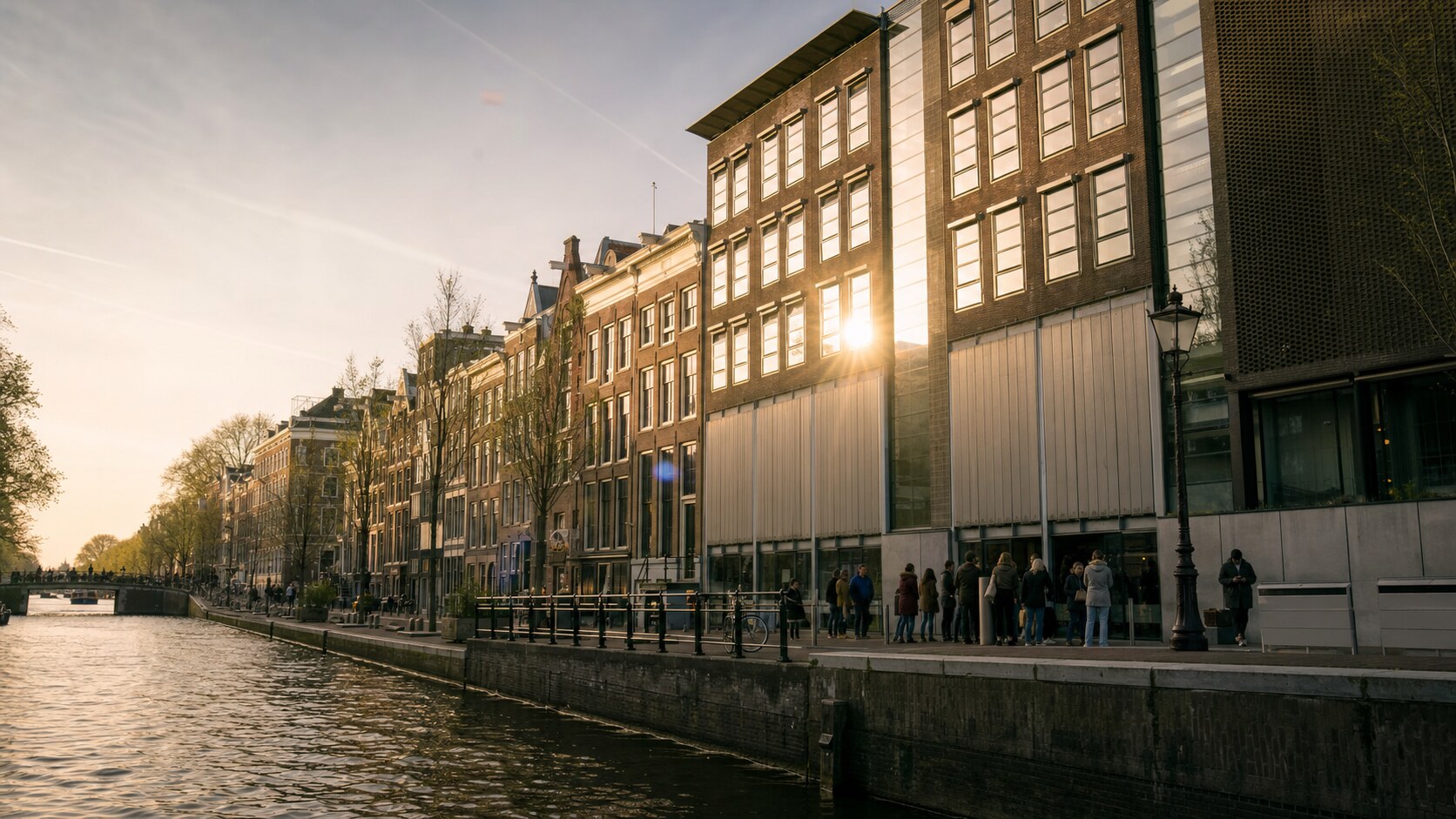 The Anne Frank House photographed at golden hour from the most popular hero-shot vantage point, with dramatic side-lighting on the structure