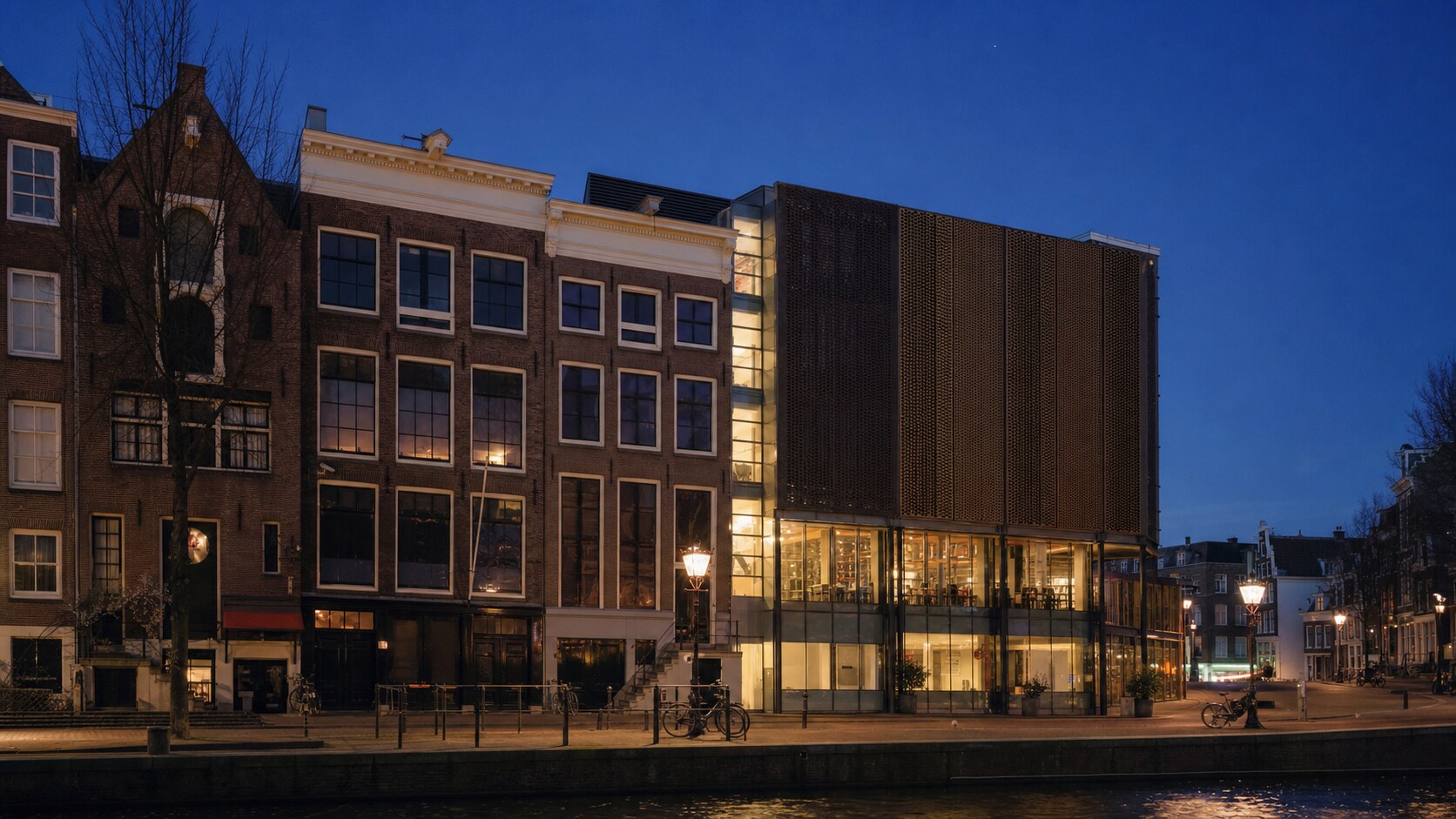 Wide blue-hour view of The Anne Frank House with cobalt sky and warm artificial lighting on the landmark