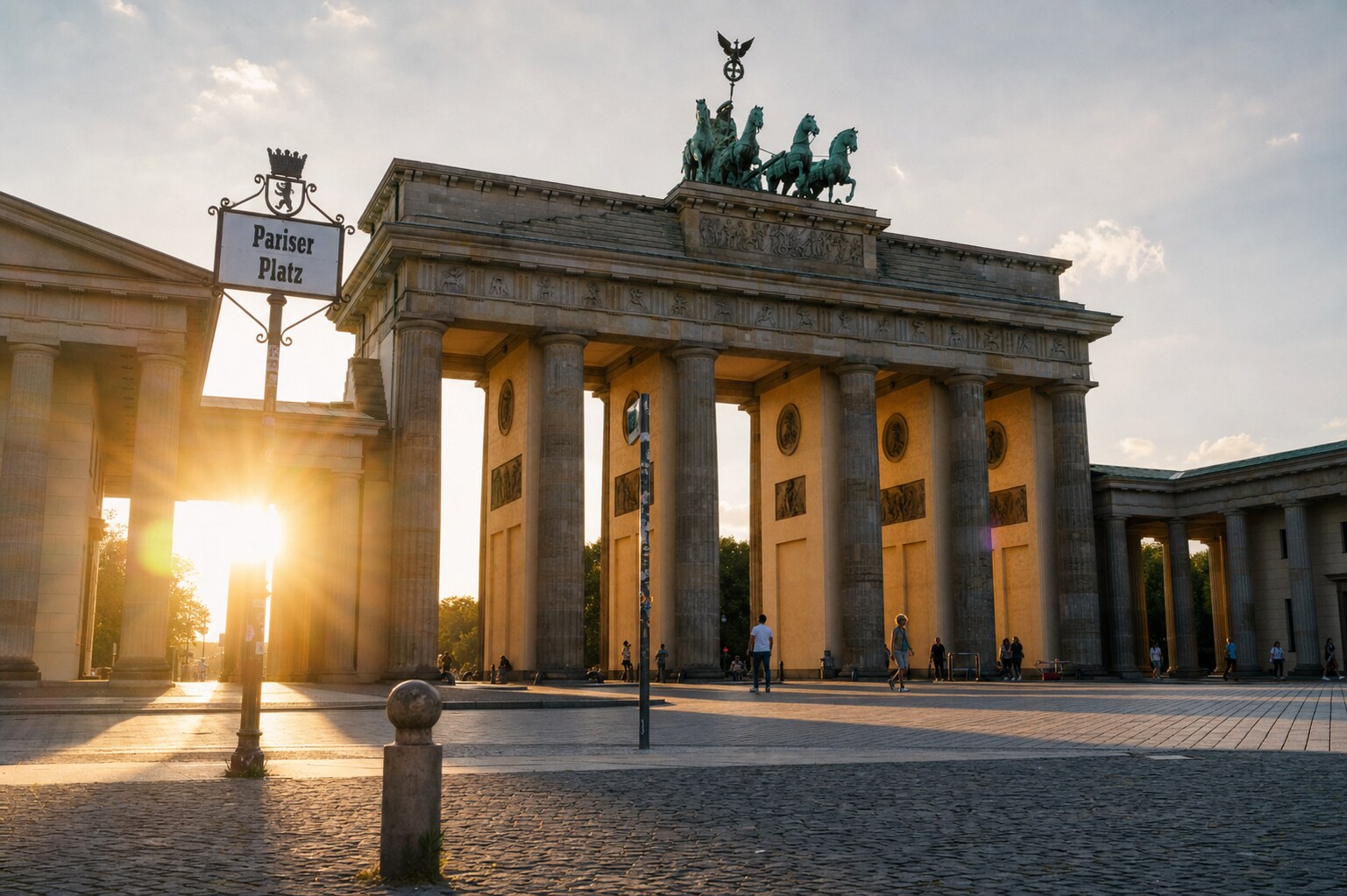 The Brandenburg Gate photographed at golden hour from the most popular hero-shot vantage point, with dramatic side-lighting on the structure