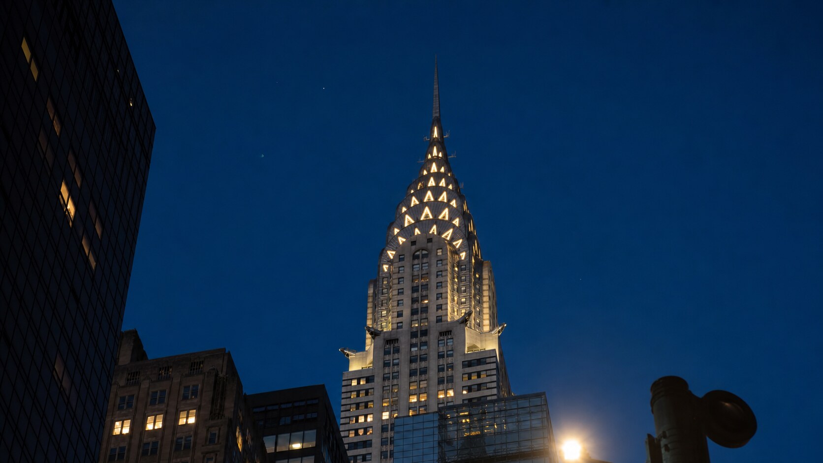 Wide blue-hour view of The Chrysler Building with cobalt sky and warm artificial lighting on the landmark