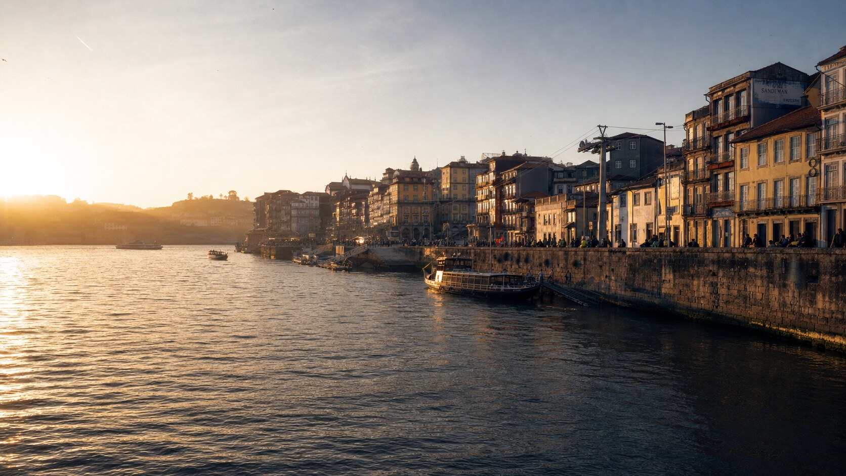 The Douro River photographed at golden hour from the most popular hero-shot vantage point, with dramatic side-lighting on the structure