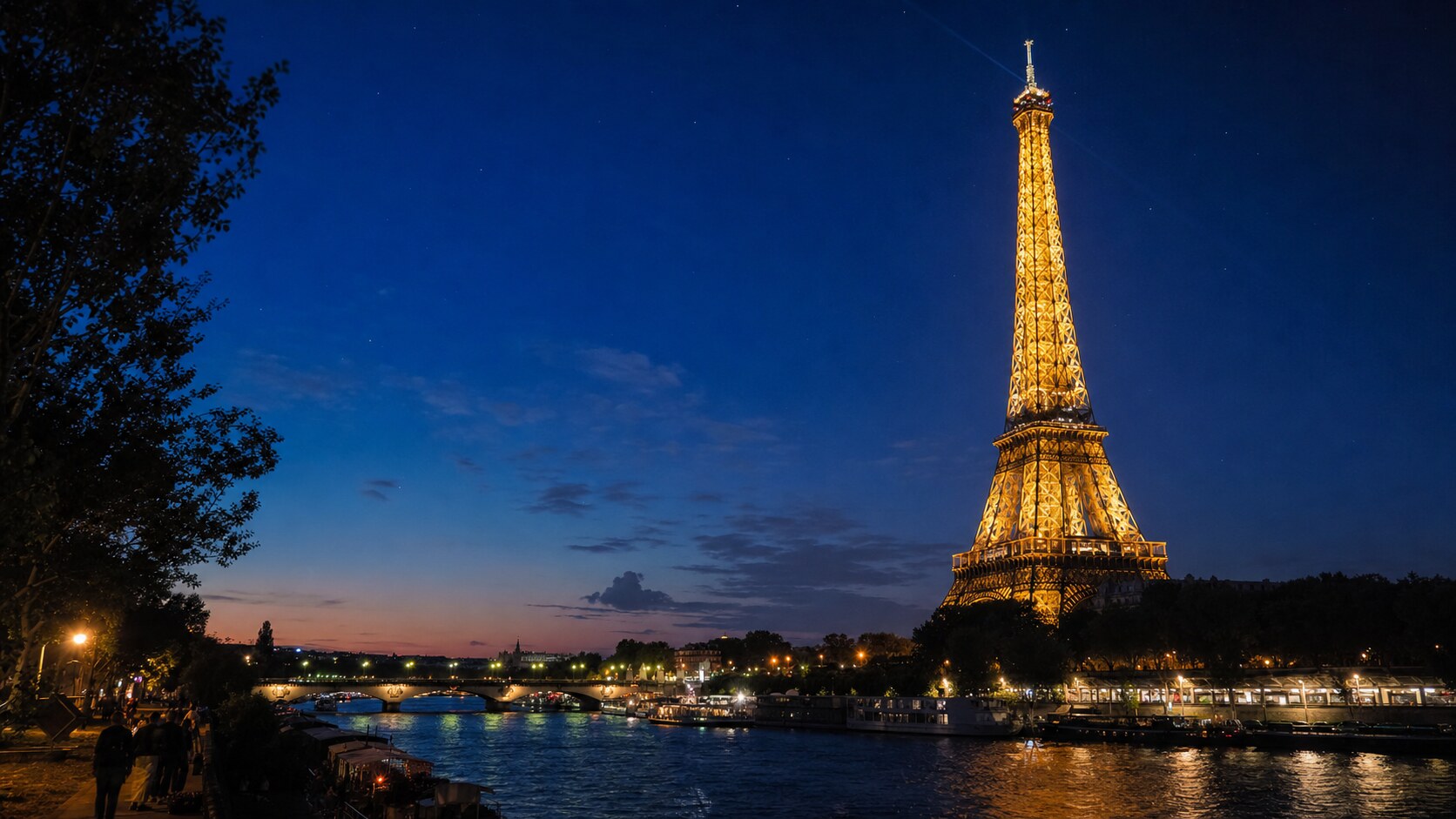 Wide blue-hour view of The Eiffel Tower Paris with cobalt sky and warm artificial lighting on the landmark
