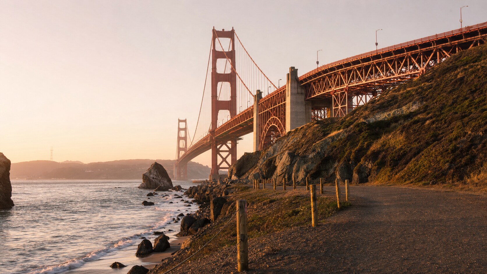 The Golden Gate Bridge photographed at golden hour from the most popular hero-shot vantage point, with dramatic side-lighting on the structure