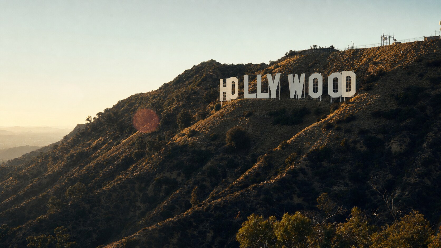 The Hollywood Sign photographed at golden hour from the most popular hero-shot vantage point, with dramatic side-lighting on the structure
