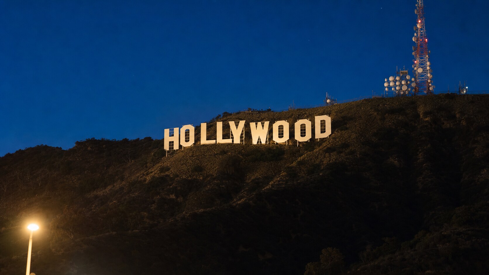 Wide blue-hour view of The Hollywood Sign with cobalt sky and warm artificial lighting on the landmark