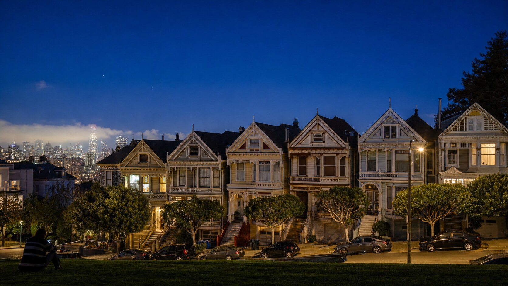 Wide blue-hour view of The Painted Ladies with cobalt sky and warm artificial lighting on the landmark