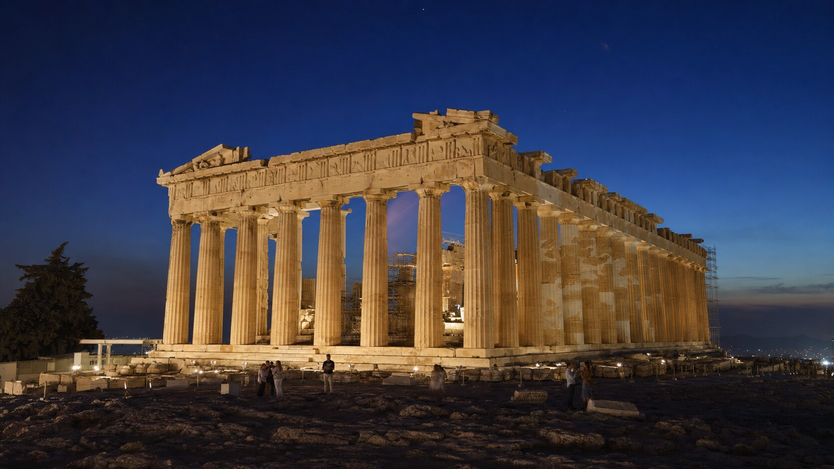 Wide blue-hour view of The Parthenon with cobalt sky and warm artificial lighting on the landmark