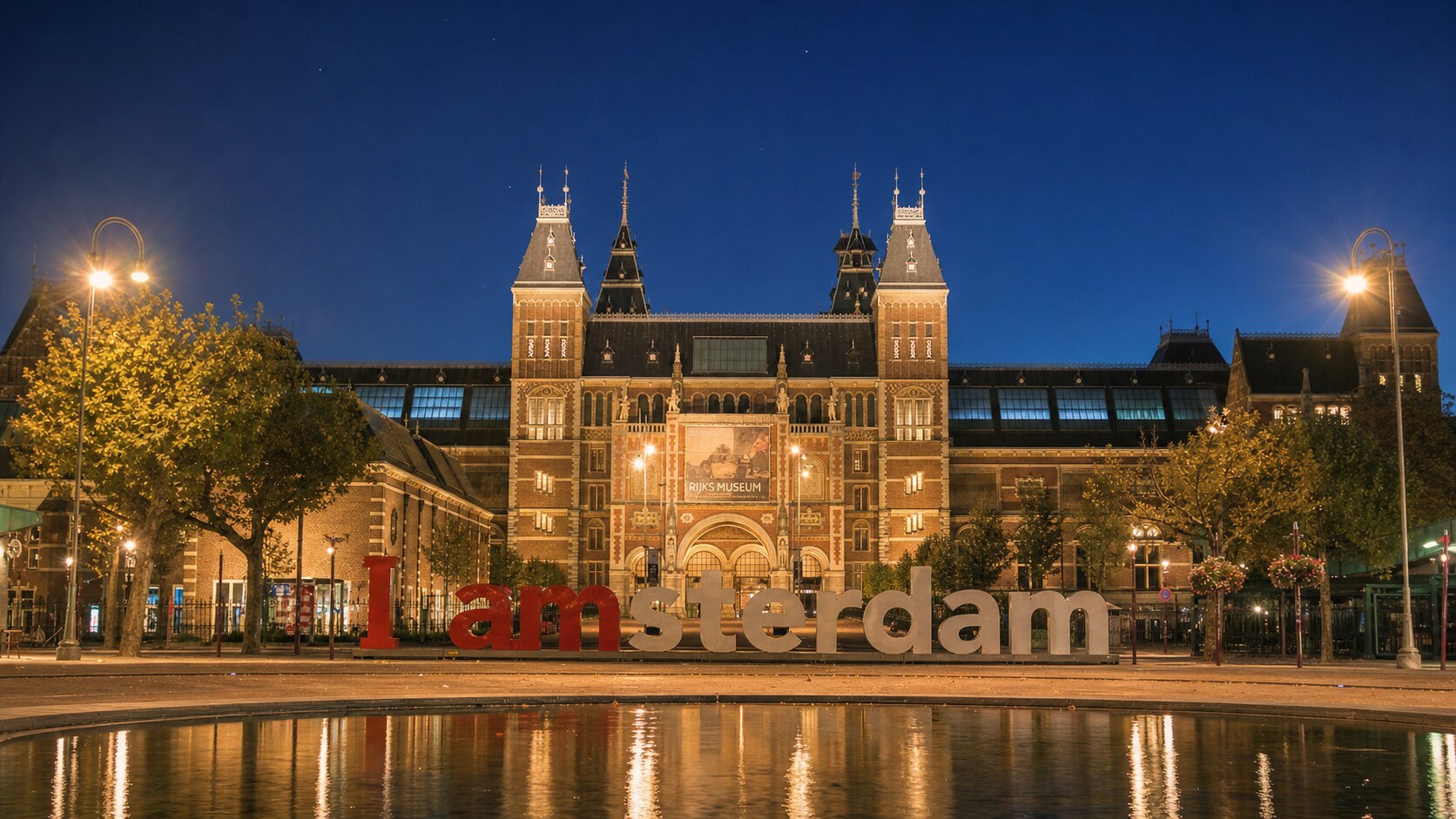 Wide blue-hour view of The Rijksmuseum with cobalt sky and warm artificial lighting on the landmark