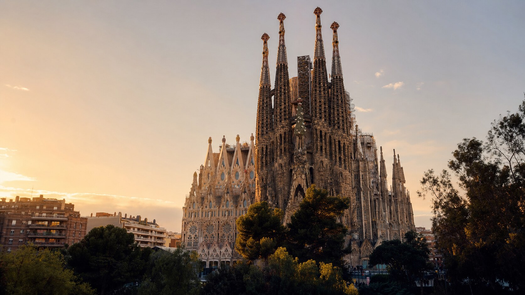 The Sagrada Familia photographed at golden hour from the most popular hero-shot vantage point, with dramatic side-lighting on the structure