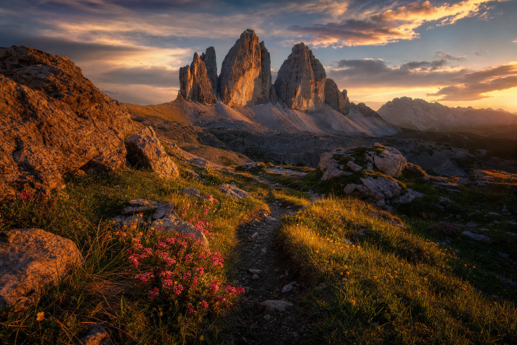 Dramatic landscape at golden hour with leading lines, foreground interest, warm directional light, photorealistic