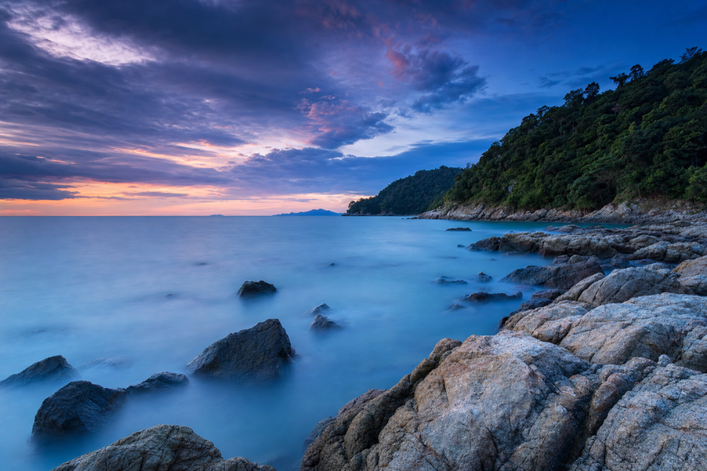 Long-exposure coastal landscape at blue hour, silky water, dramatic sky