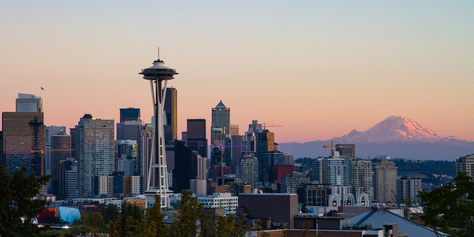 Panoramic Seattle skyline at twilight from Kerry Park, showing Space Needle, Columbia Center, and Elliott Bay under blue evening sky
