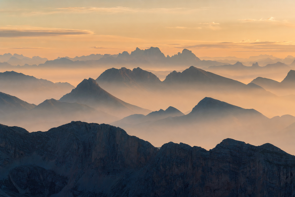 Misty mountain landscape at sunrise, layered atmospheric depth, soft pastel tones