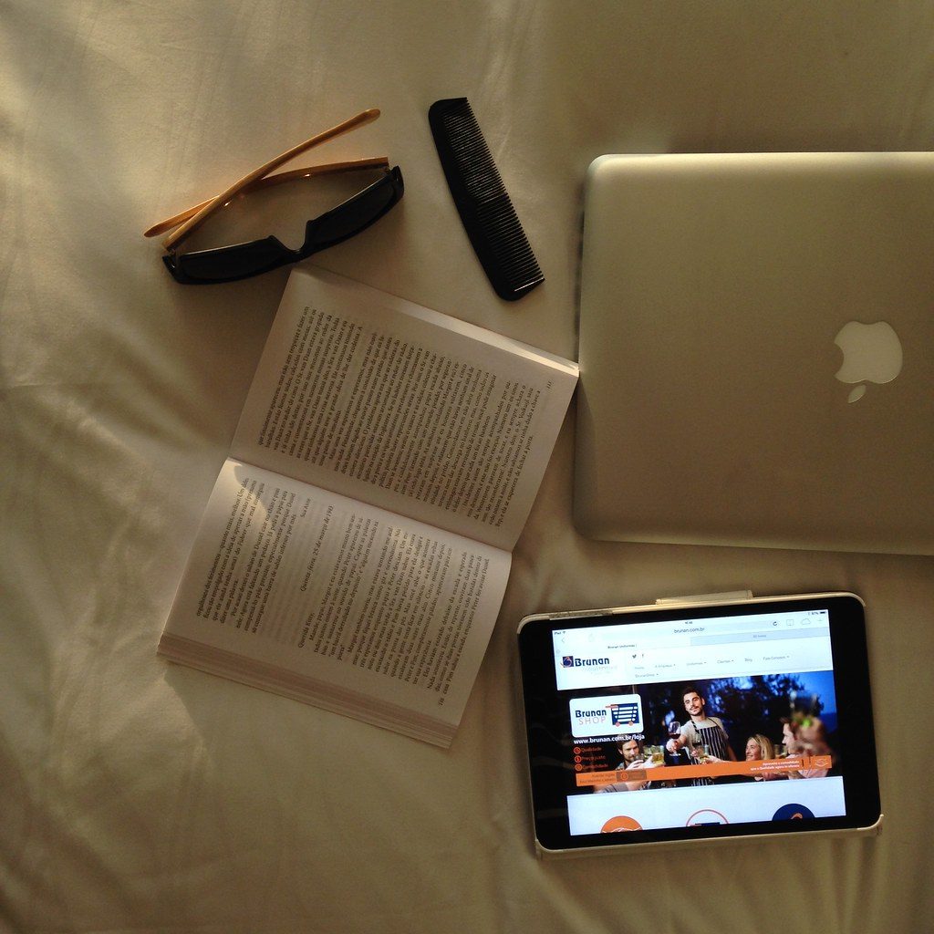 A group of diverse young photographers gathered around a table with laptops in a bright studio, discussing a photo edit