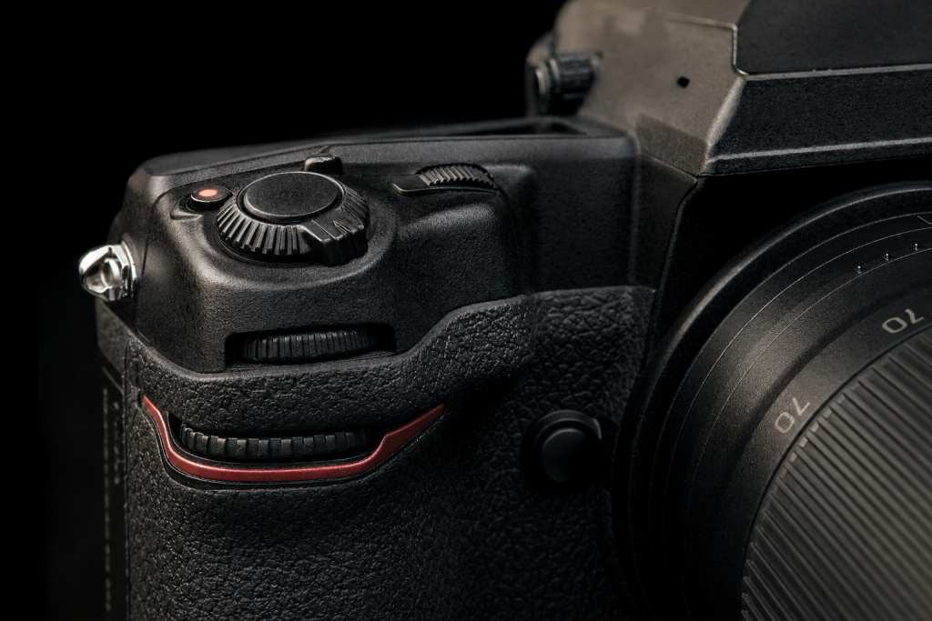 Detail shot of camera controls and grip, dramatic side lighting, macro feel, no text