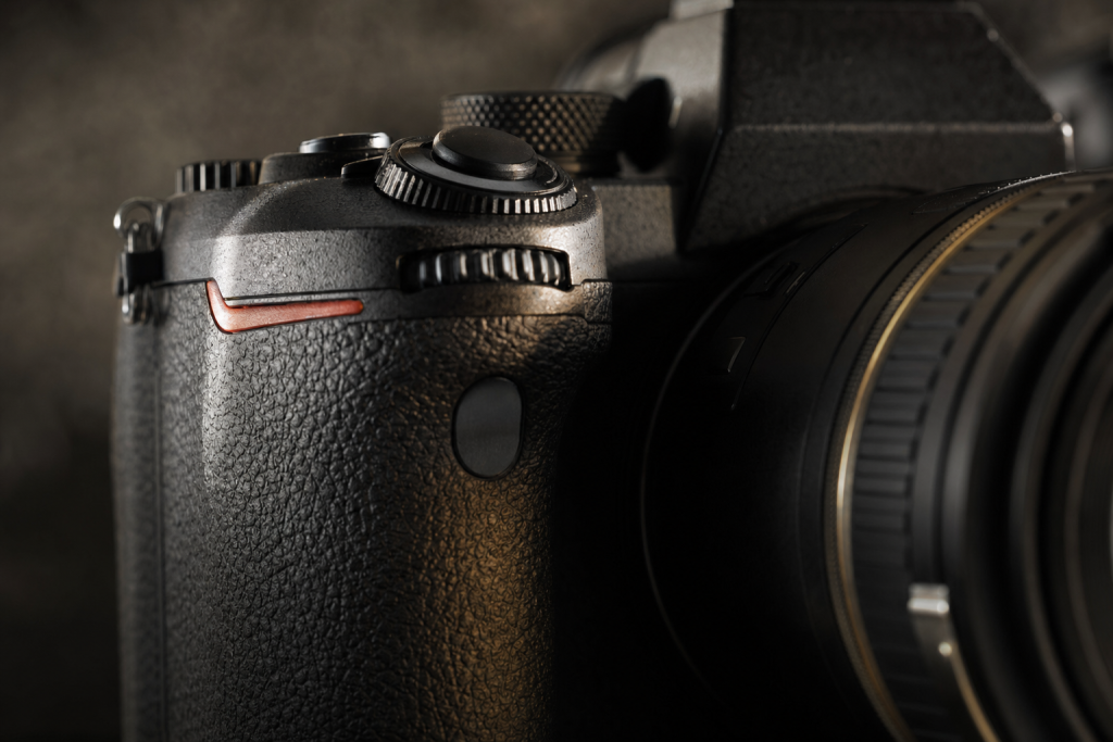 Detail shot of camera controls and grip, dramatic side lighting, macro feel, no text