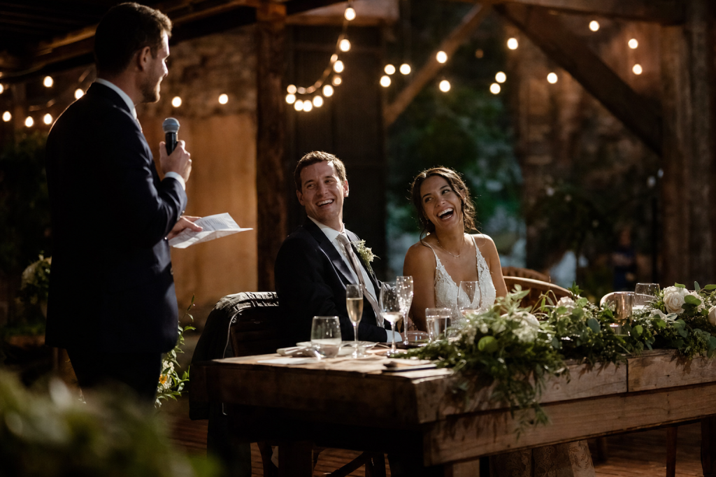 Candid wedding reception moment, warm string lights, joyful expressions, natural editorial color