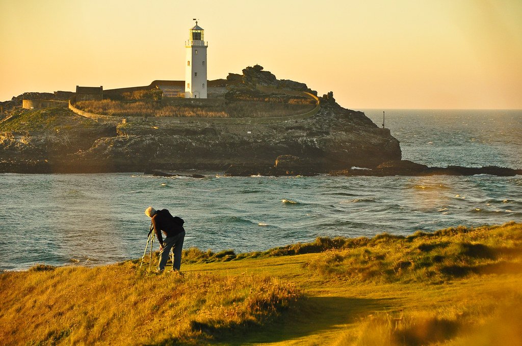 Landscape photographer with camera framing a shot in an outdoor setting at golden hour, real photographer field practice for landscape photography