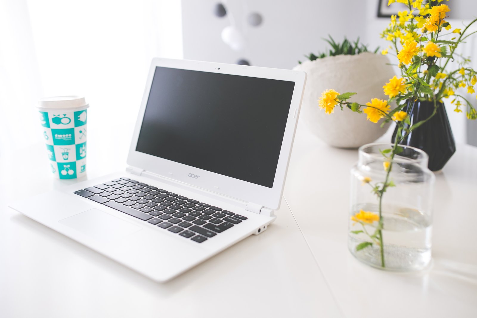Open laptop, notebook, and coffee cup on a wooden writer's desk in natural daylight, top-down freelance writing workspace