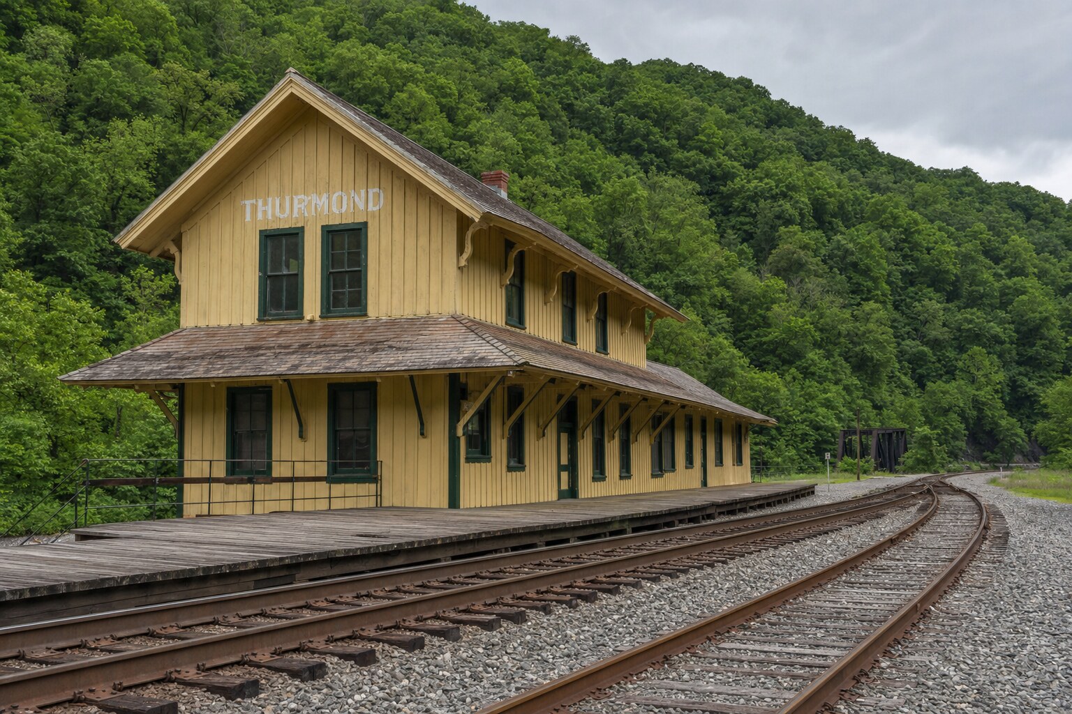 Yellow Thurmond Depot with green trim beside the C&O main line in New River Gorge