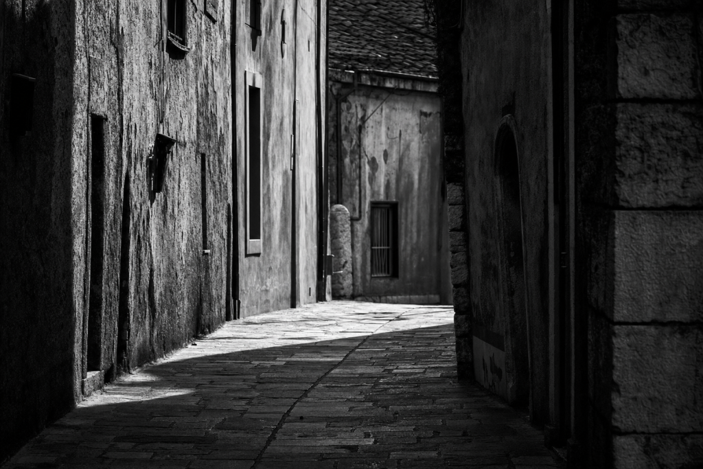Black-and-white style street composition with strong geometric shadows, high contrast, decisive moment feel