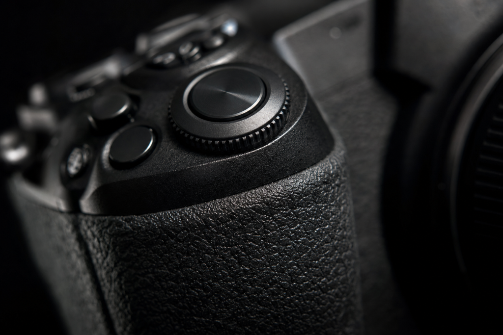 Detail shot of camera controls and grip, dramatic side lighting, macro feel, no text