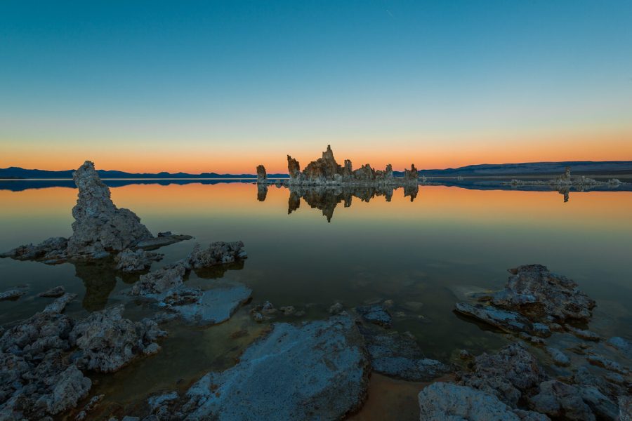 Tufa formations reflected in Mono Lake, California, beneath a blue and orange dawn sky