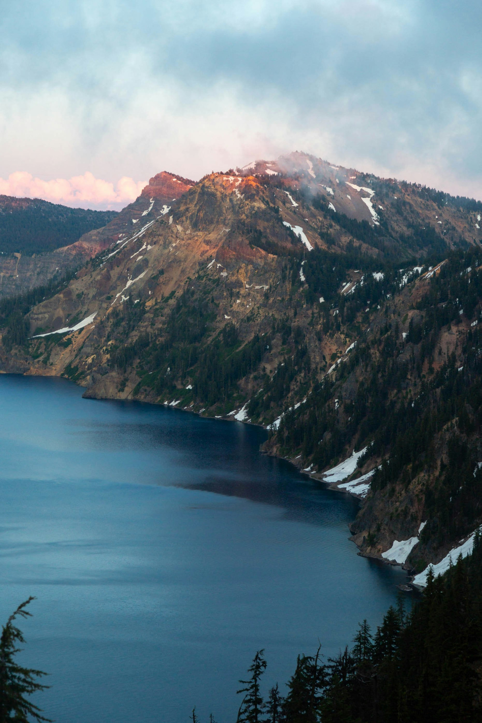 Warm sunset light on the Crater Lake caldera wall above blue water