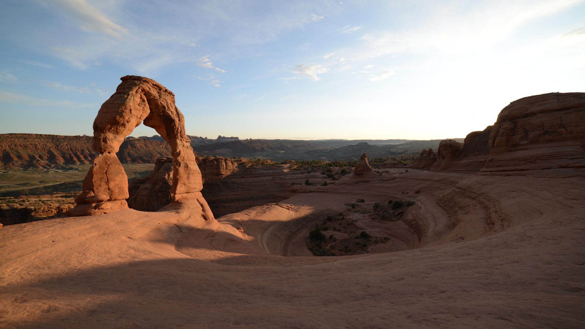Delicate Arch and its surrounding sandstone bowl in warm light