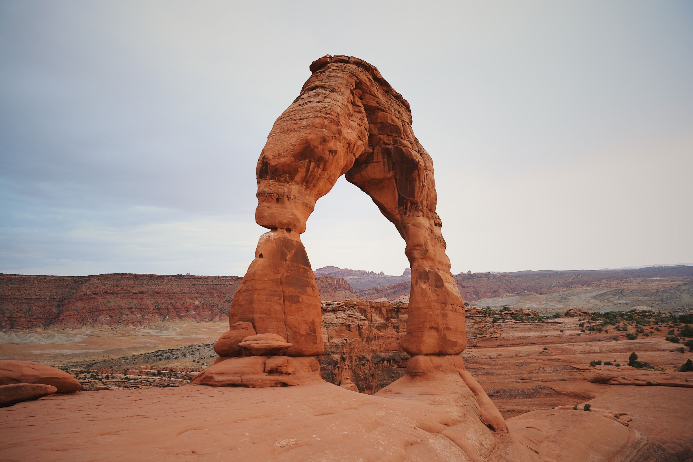 Delicate Arch beneath a muted sky above a sandstone foreground
