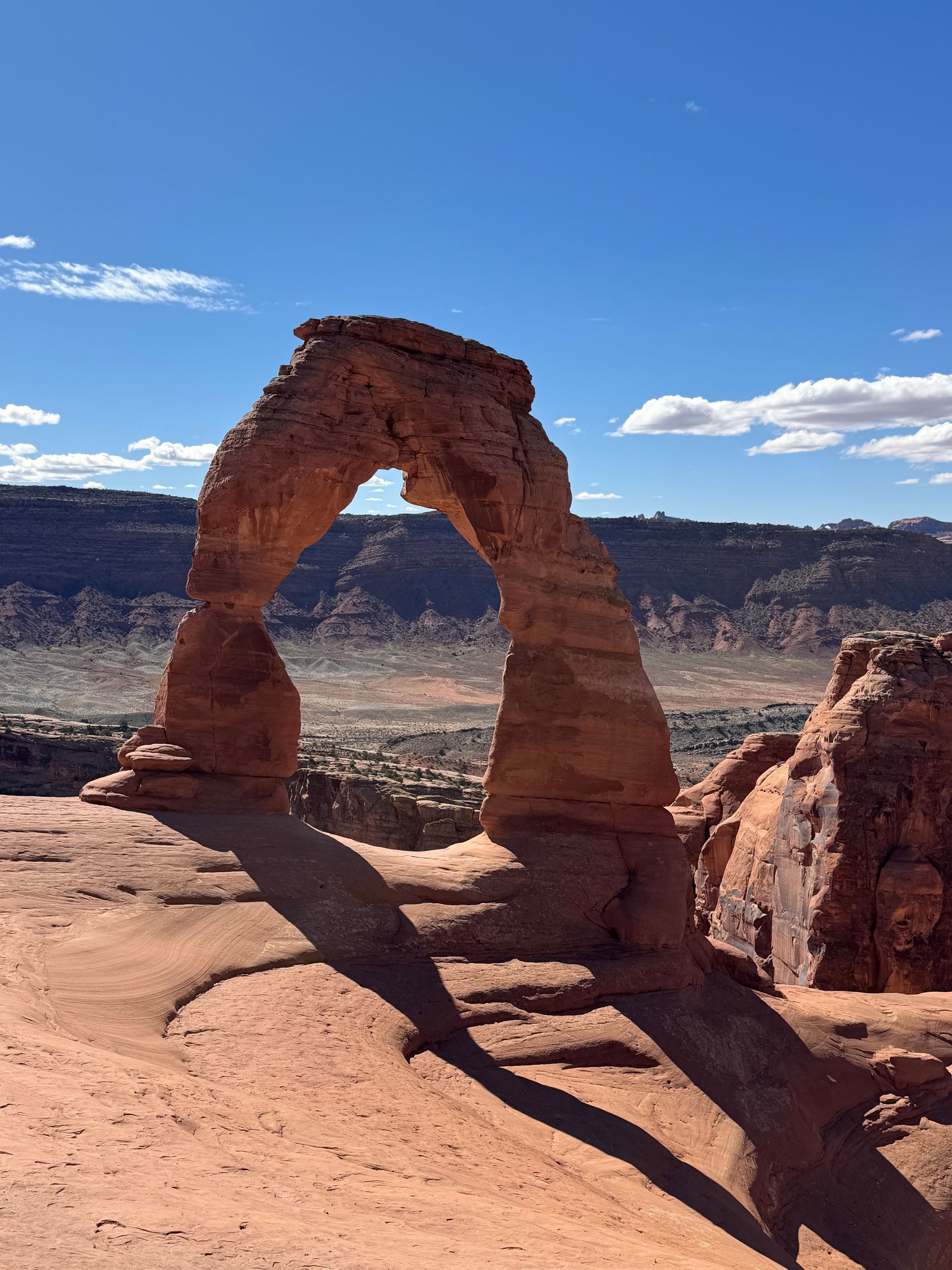 Delicate Arch casting a long shadow across pale sandstone