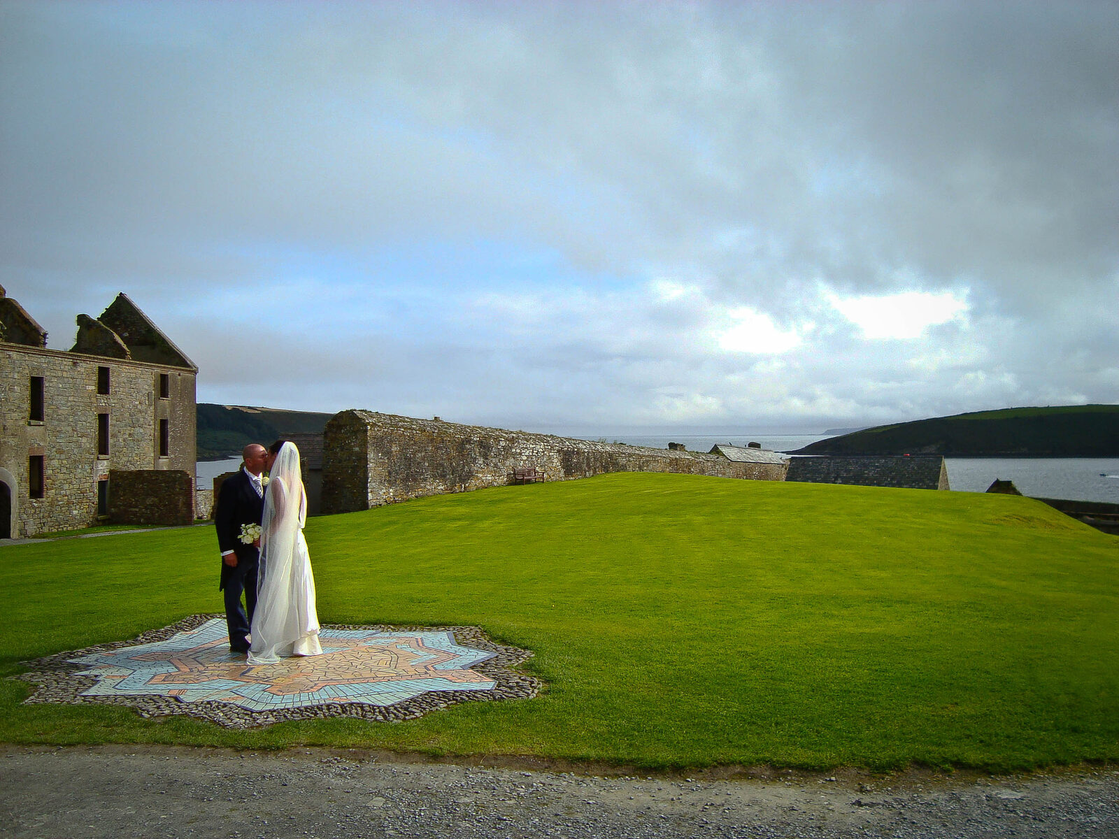 Couple embracing at sunset beside the stone battlements of Charles Fort in Kinsale, Ireland, Atlantic light behind them