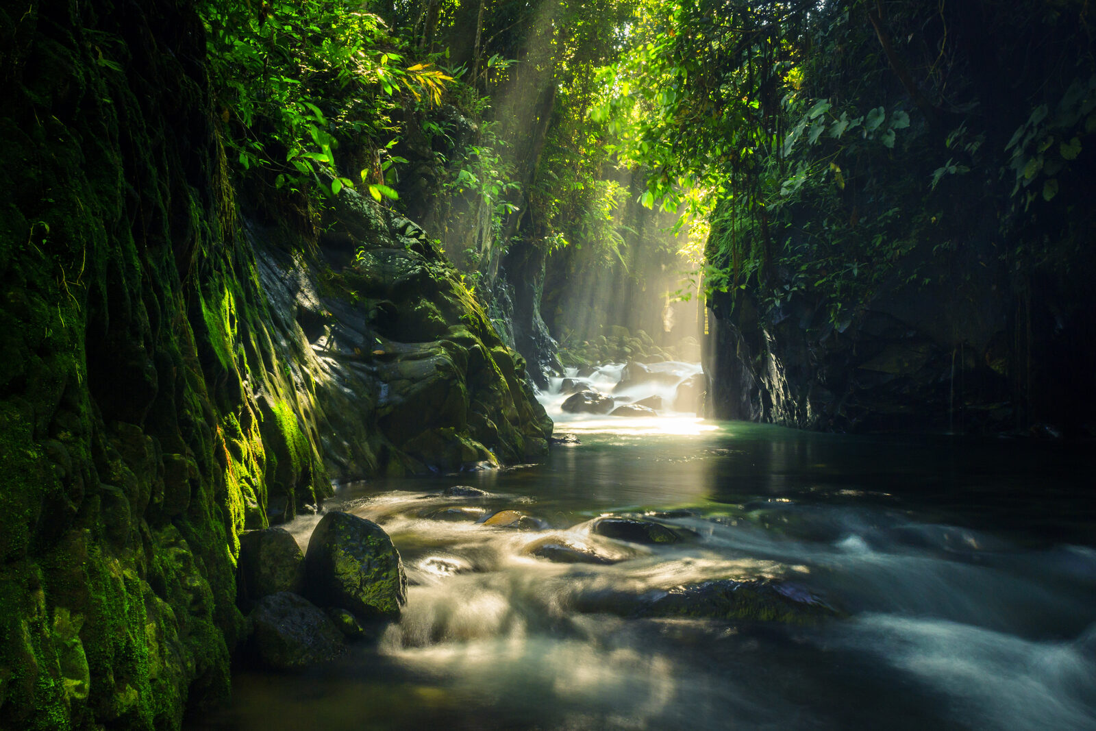 Photographer at a triple waterfall in North Bengkulu, Indonesia, long exposure silk water through dense tropical forest