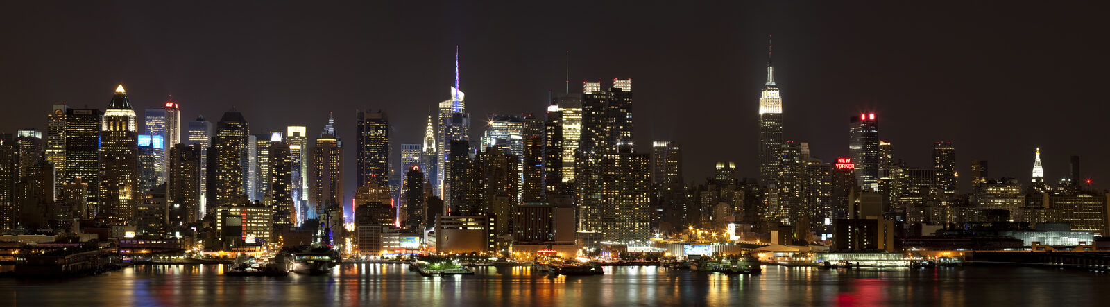 Manhattan skyline reflected in the Hudson River at blue hour, long exposure smoothing the water into a mirror surface