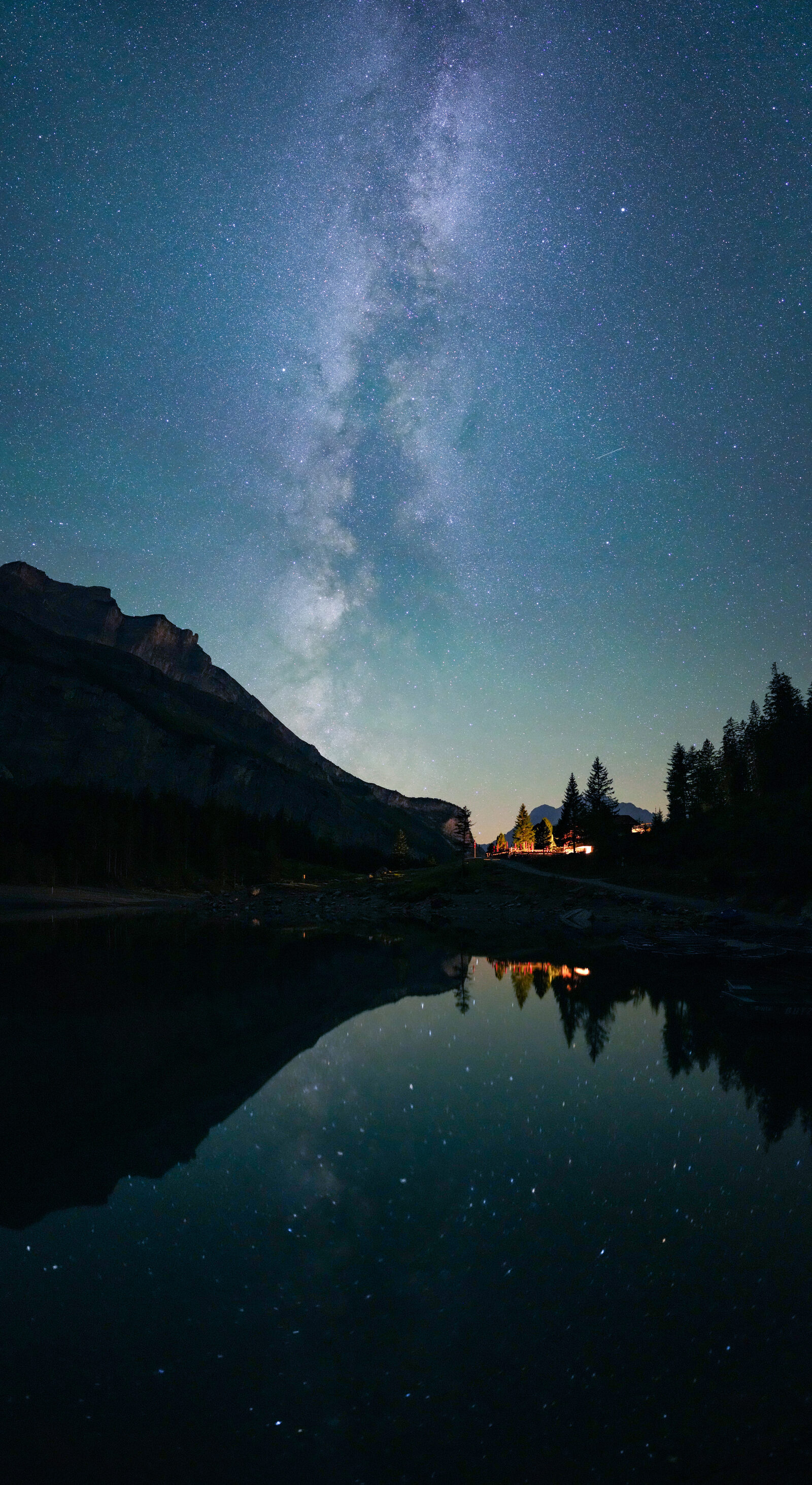 Milky Way arching over Oeschinensee lake in the Swiss Alps during the Perseid meteor shower, stars reflected in still water