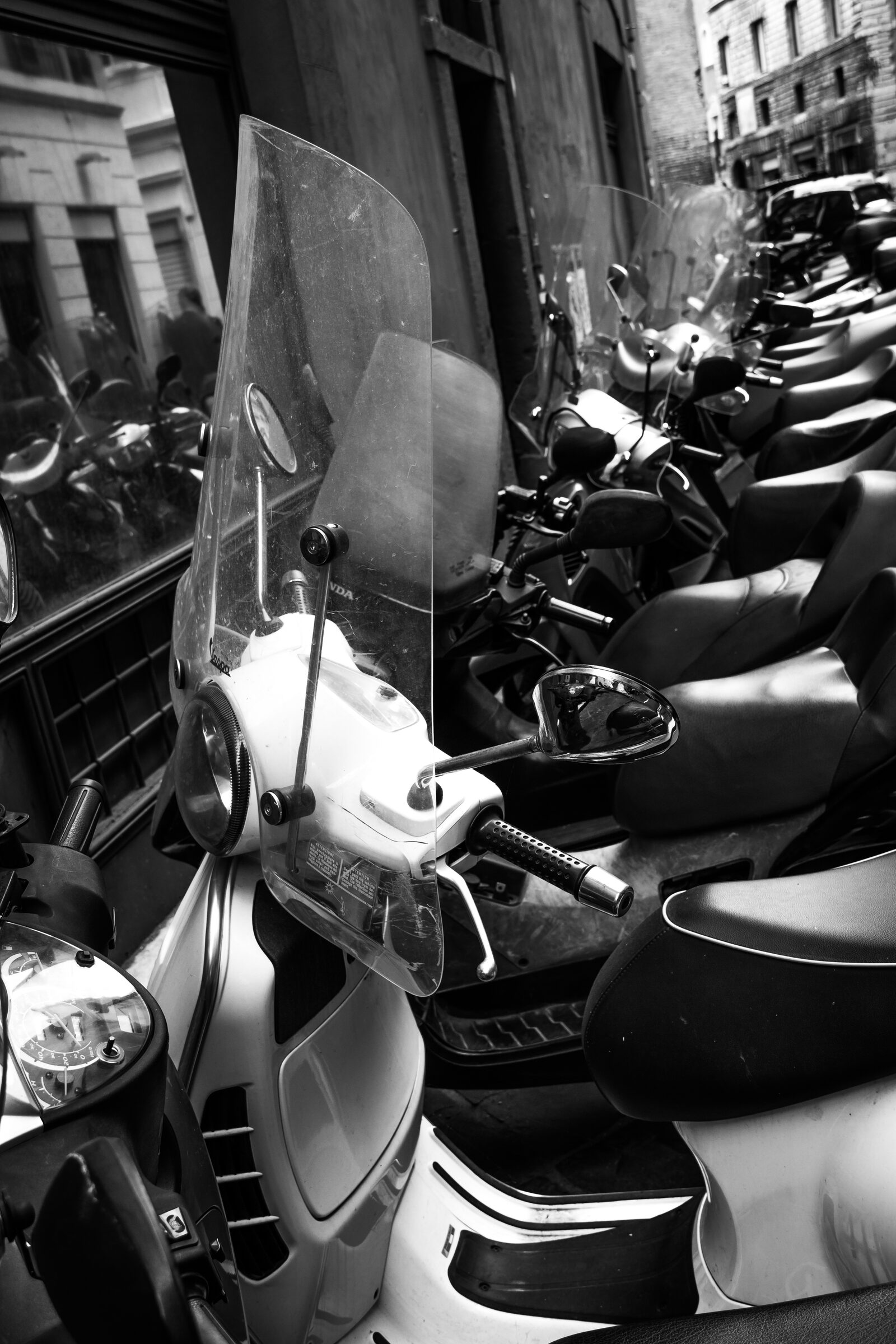 Row of parked motorcycles on a Roman cobblestone street, black and white geometry and texture dominating the frame