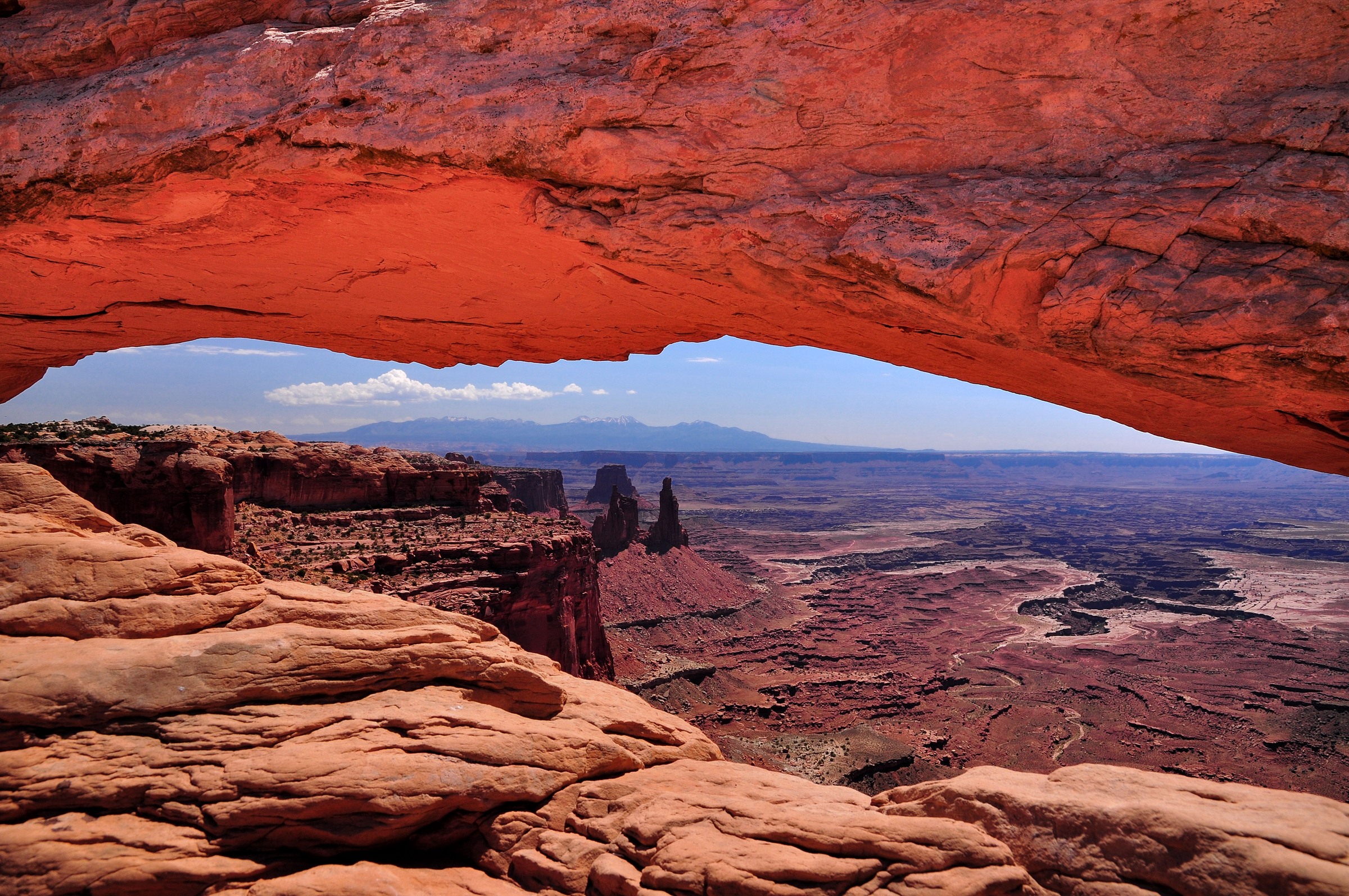 Red sandstone underside of Mesa Arch above layered Canyonlands terrain
