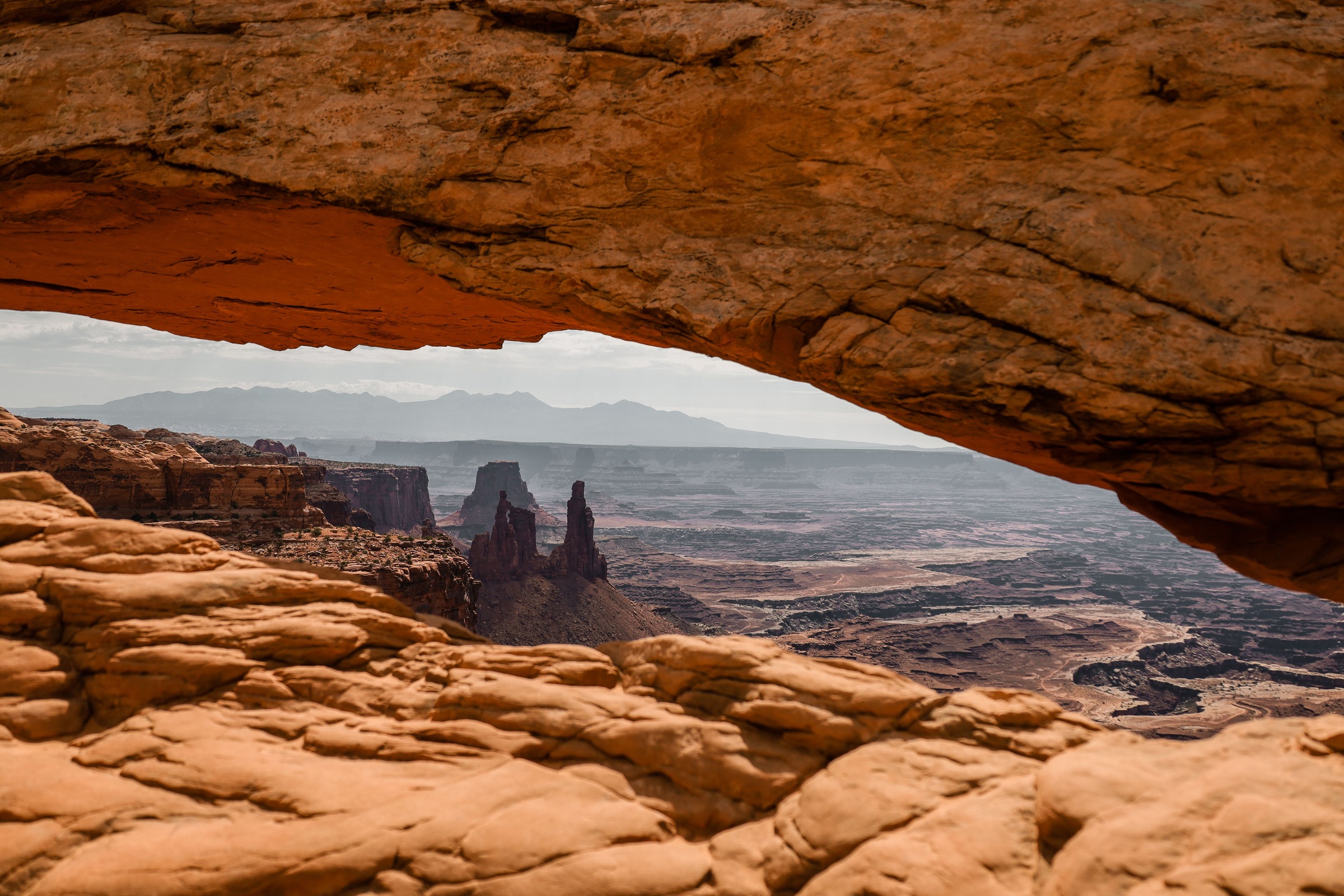 Shadowed rock framing a distant canyon view through Mesa Arch