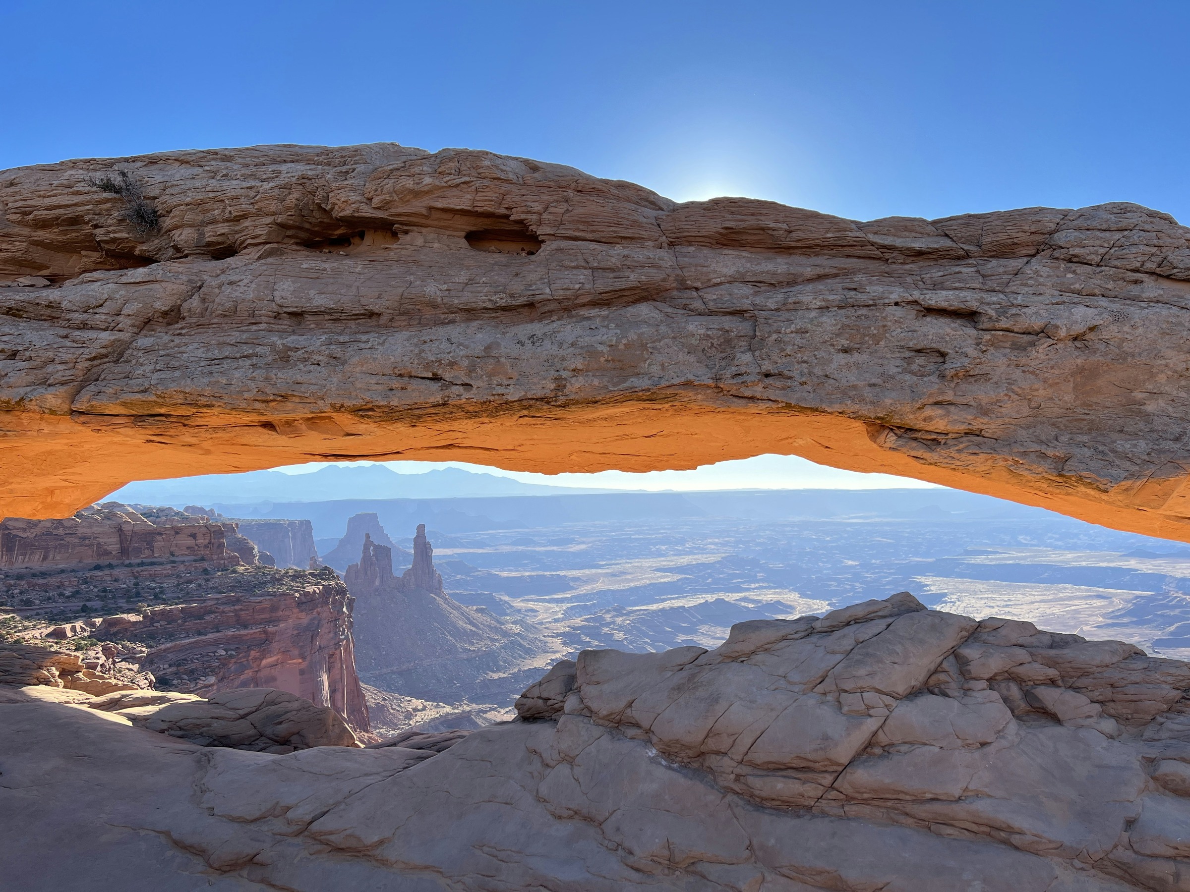 Mesa Arch framing distant canyon towers beneath a blue sky