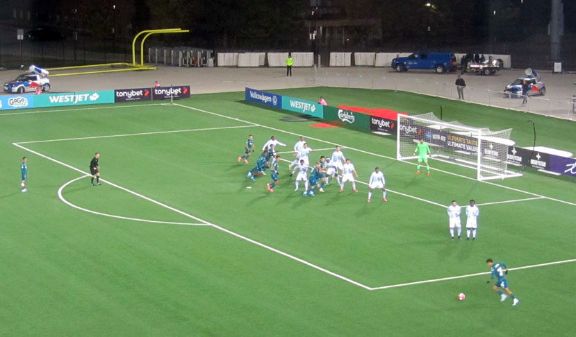 Soccer player Jorge Guzman frozen mid-air during a free kick with leg extended and ball in motion