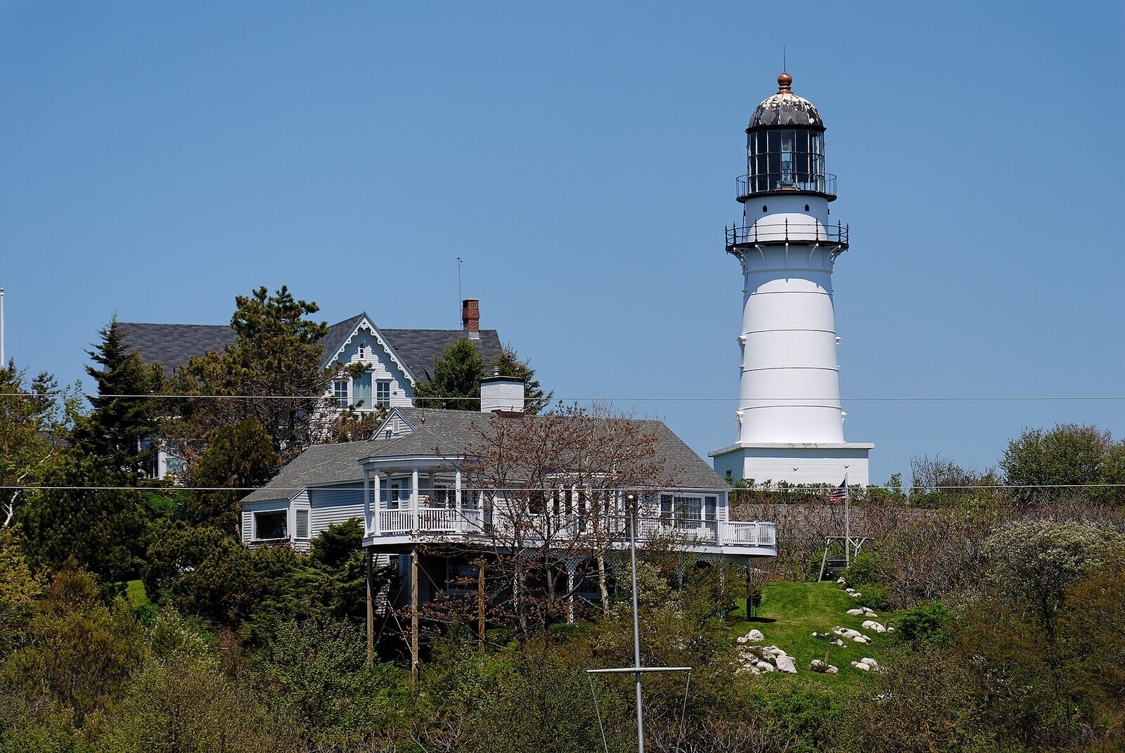 Composition of Cape Elizabeth Light tower against coastal pines in Cape Elizabeth, Maine demonstrating a travel photography composition.
