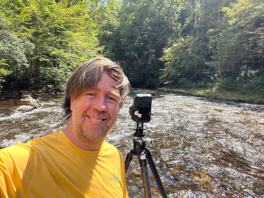Photographer with carbon-fiber tripod on location in Western North Carolina demonstrating field-stability technique for a carbon-fiber tripod buyer-guide tutorial.